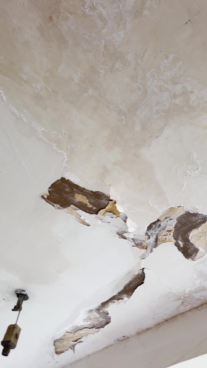 Rotten cracked damp wall or ceiling in old broken-down building vertical pov video. Phone camera point of view on paint falling from roof. Neglected infrastructure or weathered conditions in city