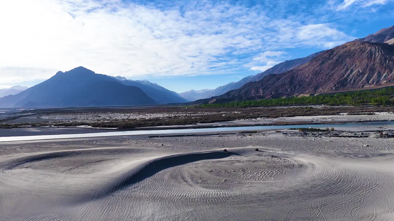 Aerial drone shot showcasing the contrasting landscapes of Nubra Valley, where desert meets green fields.