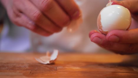 cook peels an egg on a wooden board