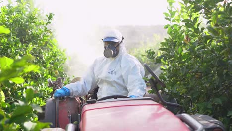 agricultor en ropa protectora rociar pesticidas