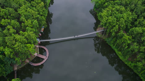 Aerial-view-of-dense-forest-and-in-centre-lake-stays-still-reflecting-the-cloudy-sky