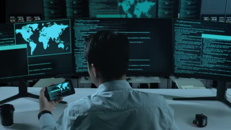 back view of asian man developer working with mobile phone while write code with multiple computer screens in the office