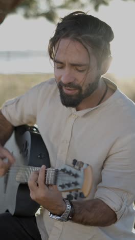 hombre tocando la guitarra acústica al aire libre