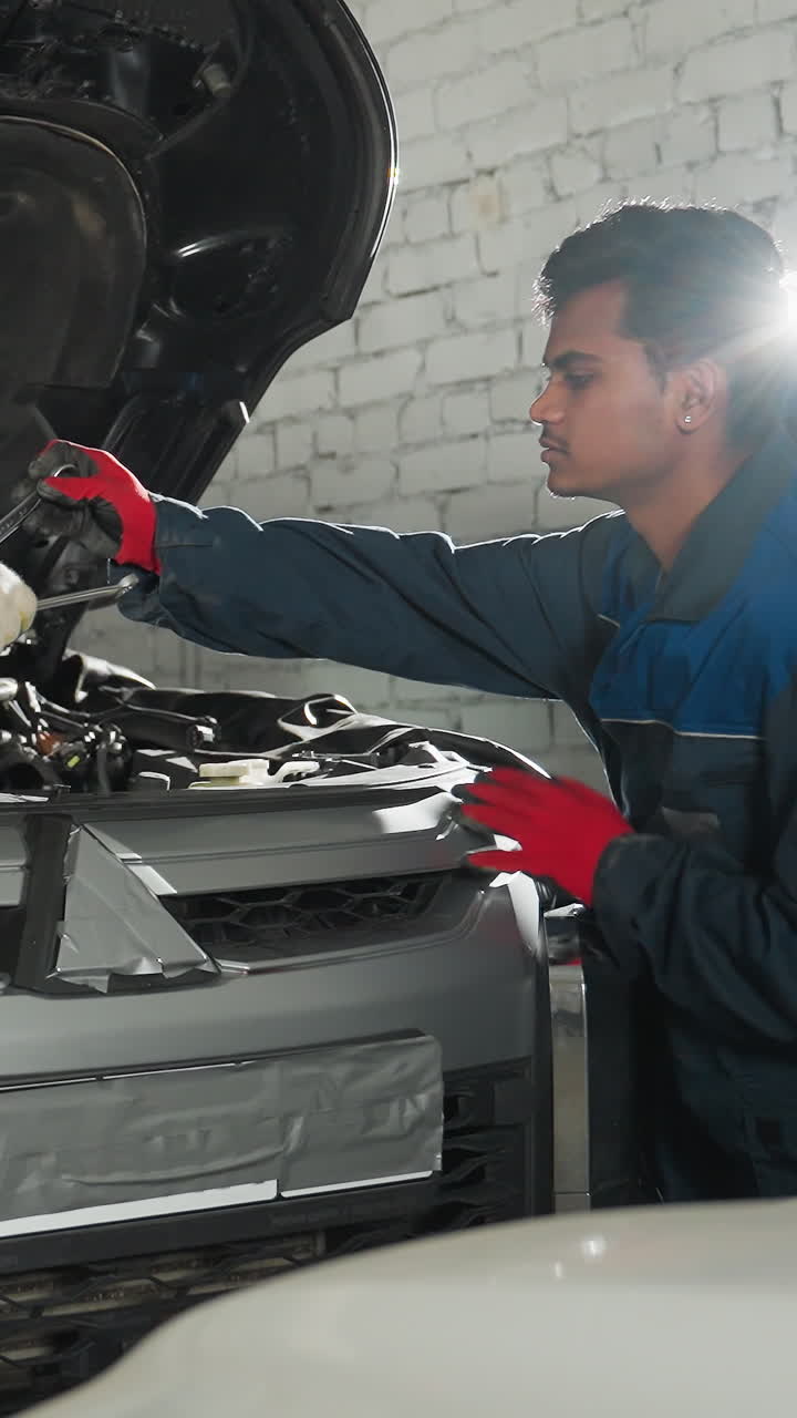 dos mecánicos en uniformes azules trabajan en el motor del coche, intercambiando herramientas y haciendo reparaciones en un taller profesional, con una luz brillante brillando en el fondo