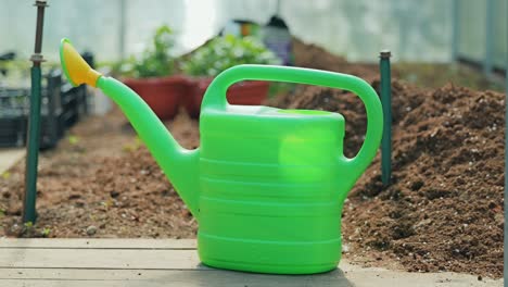 slow zoom out from plastic watering can placed near soil beds in spring sunlight