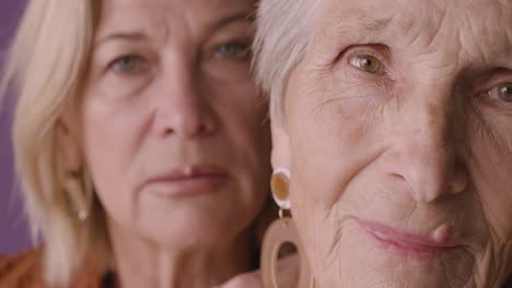 Close-Up-View-Of-Blonde-Senior-Woman-With-Short-Hair-Posing-With-Blonde-Mature-Woman-On-Purple-Background