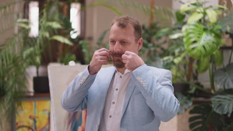 painter adjusts mustache in art studio. creative energy of art studio where personal aesthetics intertwine with act of painting. personal grooming