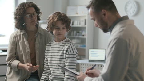 una mujer y su pequeño hijo consultando con un pediatra en la oficina médica