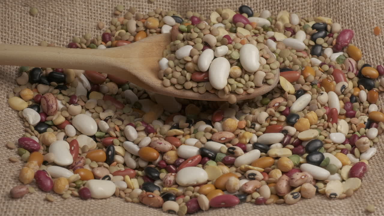 Dry mixed legumes on wooden spoon slow motion, organic agriculture, Mediterranean healthy diet