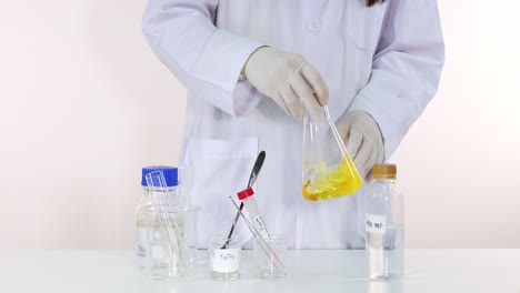 scientist stirring yellow substance in a laboratory