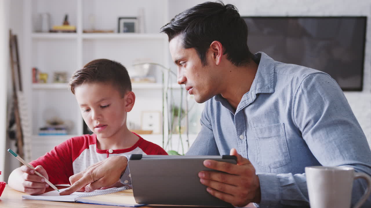 hispano pre-adolescente sentado en la mesa de comedor trabajando con su tutor de la escuela en casa, de cerca
