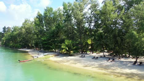 Peaceful-sandy-beach-with-the-sunbeds-for-the-couples-in-the-shadows-of-the-tall-exotic-trees