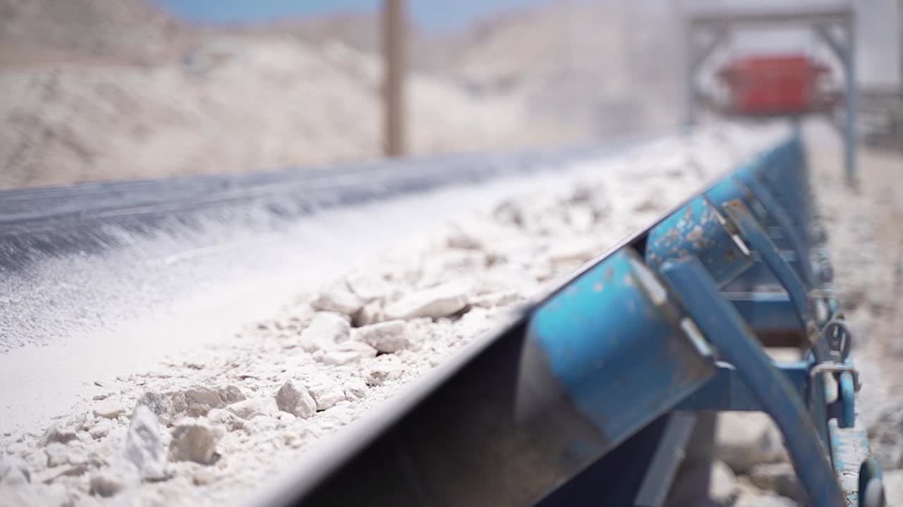 Plaster rocks coming into focus as they are being transported on a conveyor belt.