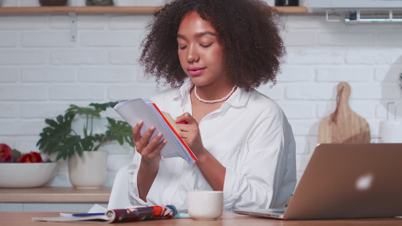 Young hispanic female writes data from computer sits at home and self educating