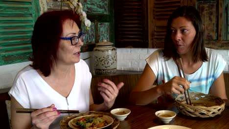 women eat seafood and chicken skewers at the restaurant and talk