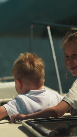 positive little boy and girl observe nature sailing on motorboat in sea on sunny day. brother and sister enjoy water trip sailing yacht in ocean on holiday