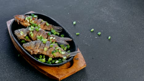 fried fish carps on a tray sprinkle with green onions.