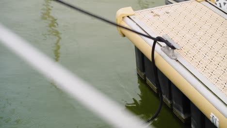 close up of boat leaving behind the untied rope at bollard sailing dock