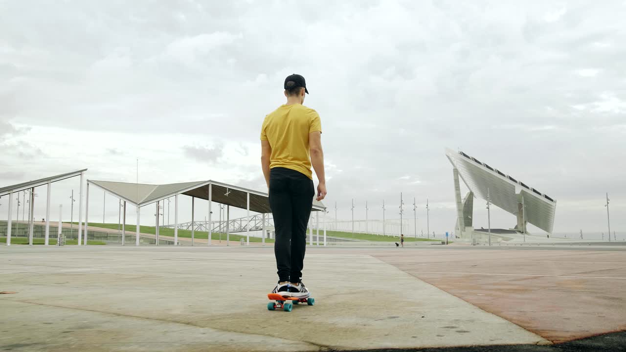 Young Attractive Trendy Man skateboarding fast under a solar panel on a morning sunny day with an urban city background in slow motion