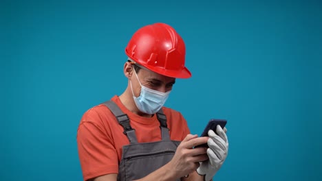 construction worker in hard hat and mask using smartphone