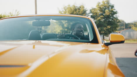 man driving a yellow convertible