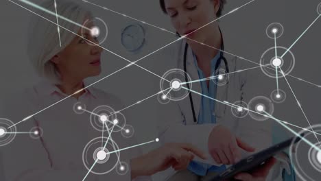 Animation-of-network-of-connections-over-female-doctor-with-digital-tablet-talking-to-female-patient