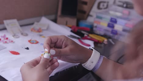 Closeup-of-woman´s-hands-making-crafts-with-colorful-little-beads,-needle-and-thread-005