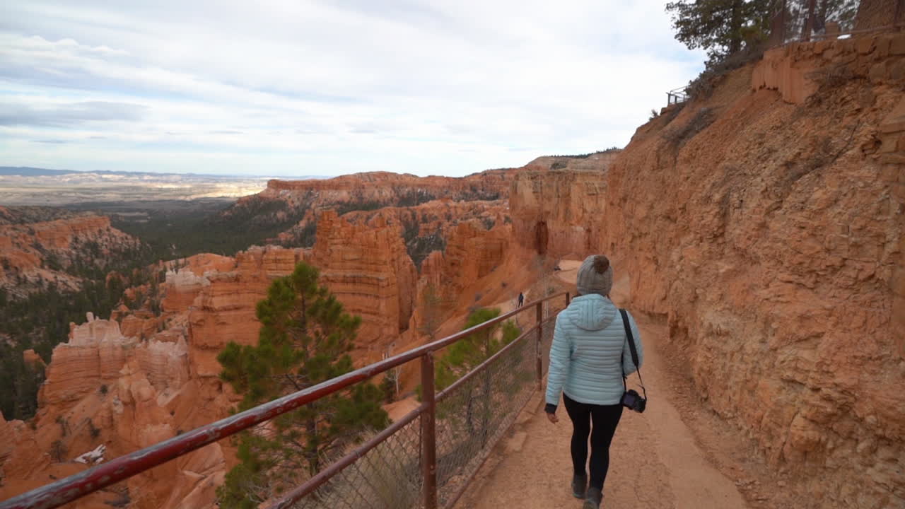 mujer caminando por un sendero de senderismo con una vista impresionante del parque nacional bryce canyon paisaje, cámara lenta, vista de atrás