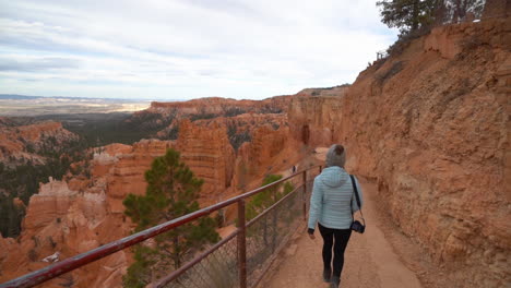 woman walking on hiking trail with stunning view on bryce canyon national park landscape, slow motion, back view