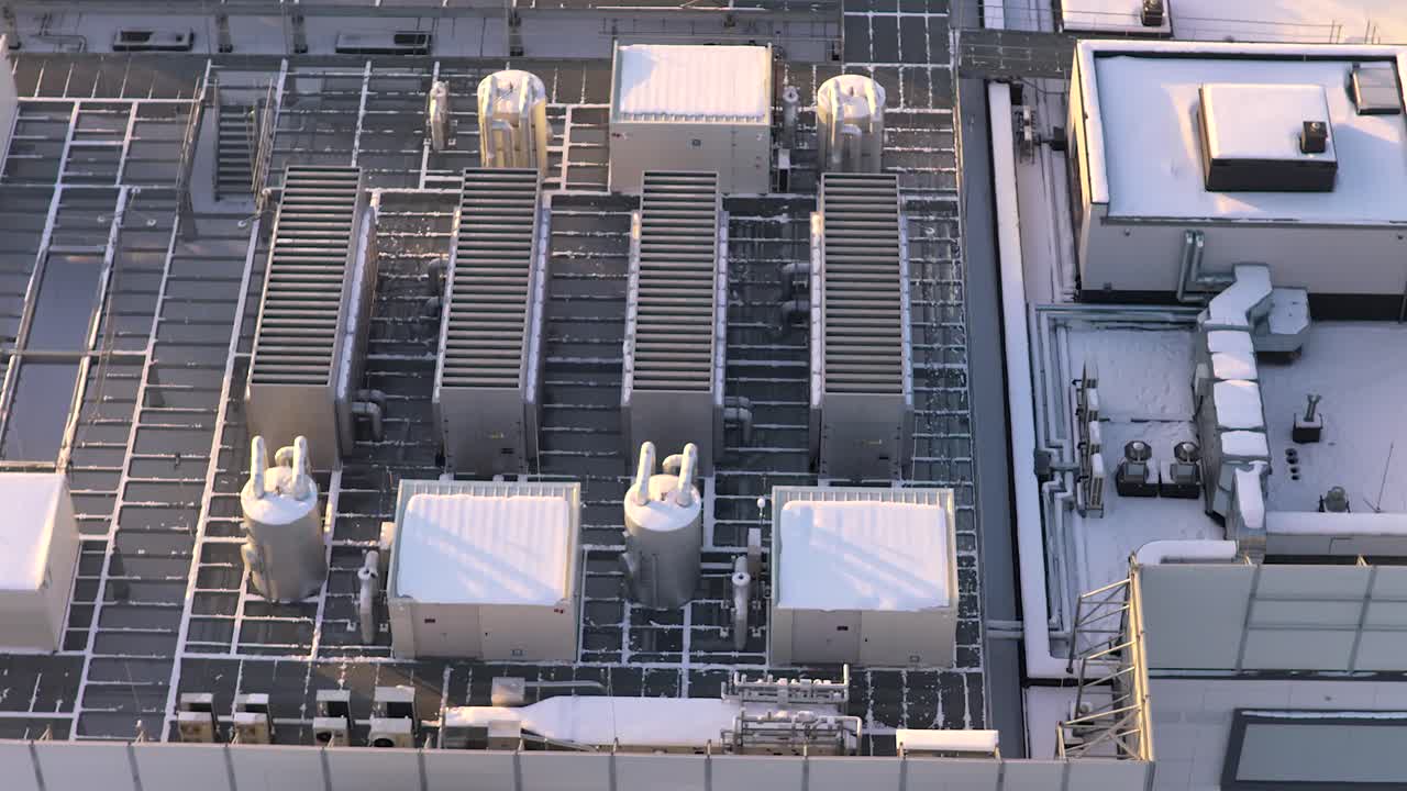 Modern data center rooftop featuring complex cooling and air conditioning systems. Industrial hvac units covered in snow during a cold winter day