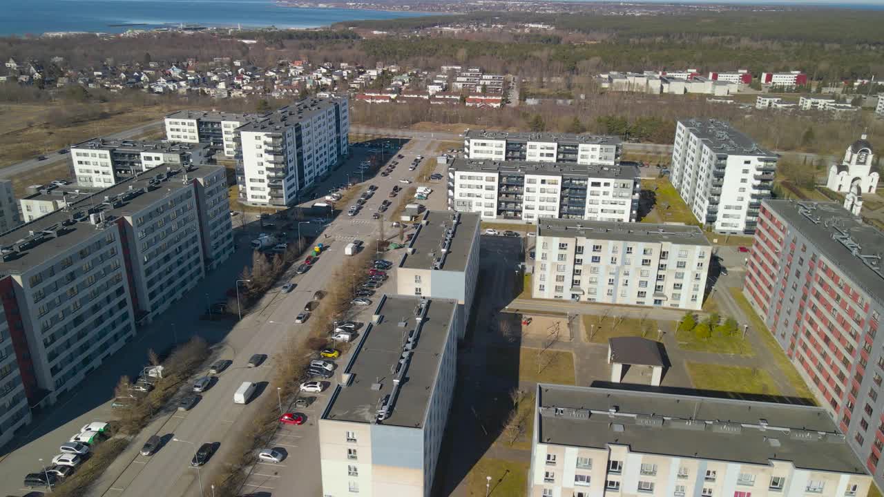 Aerial drone footage of large new apartment complexes and houses in Lasnamäe Estonia during a spring sunny day with horizon visible in the background and blue sea also that is the Baltic sea.