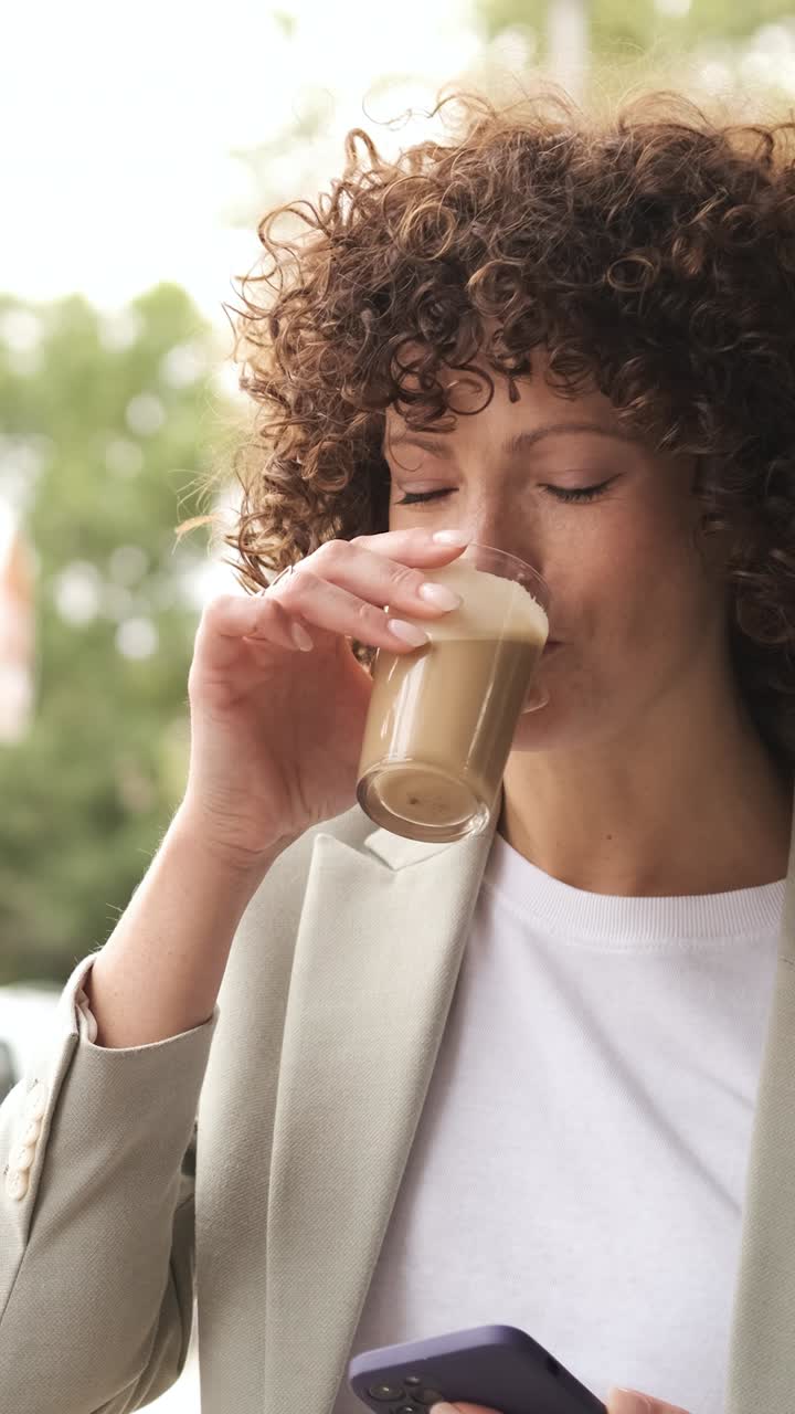 Businesswoman enjoying coffee break using smartphone. Vertical