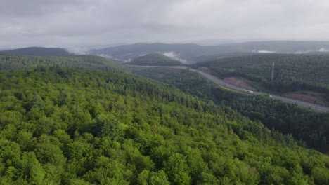 cinematic and panoramic drone 4k footage from afar of a long highway through a large and dense german forest near the city of weibersbrunn