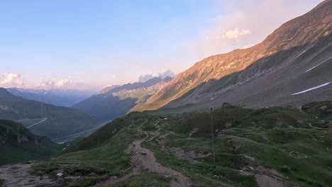 a high-altitude trail overlooks the switchbacks of nufenen pass and the vast gries valley during sunset in the lepontine alps, ticino, switzerland, with golden light on the rugged slopes