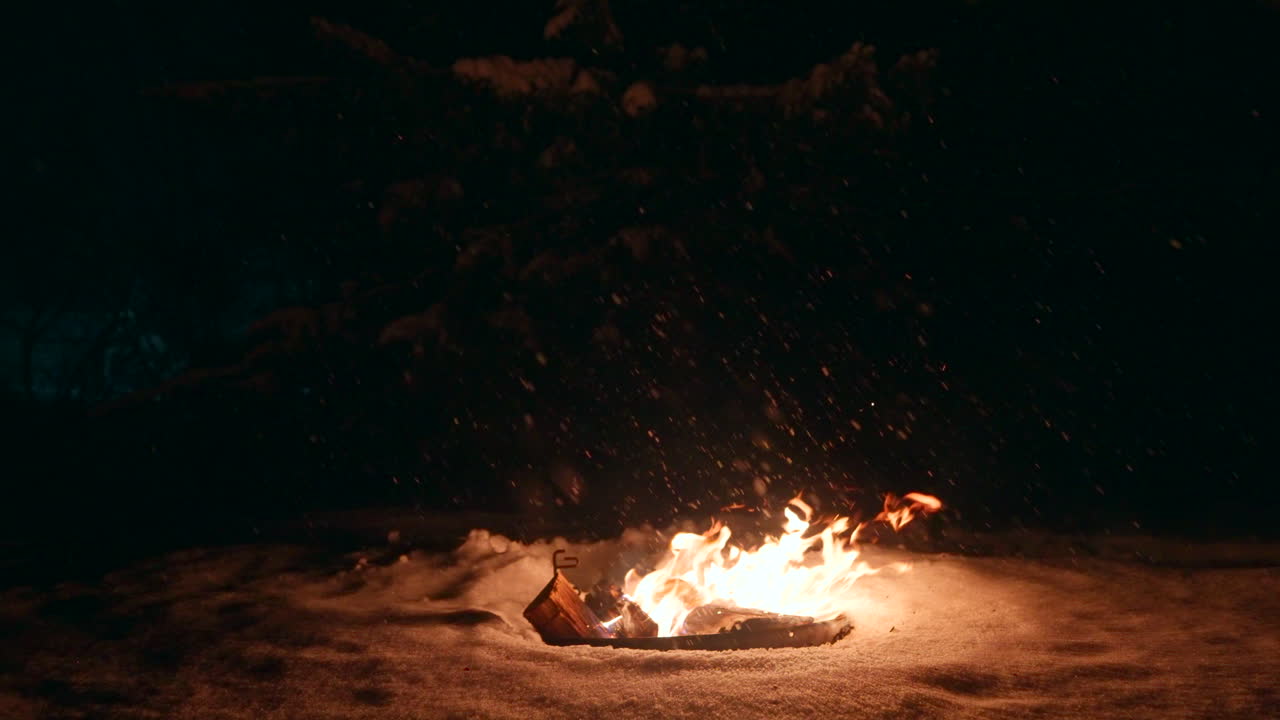 밤에는 눈이 내리며, 눈에 둘러싸인 뜨거운 불꽃과 함께 나무 불로 조명됩니다.