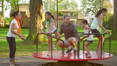 family playing on a merry-go-round at a park