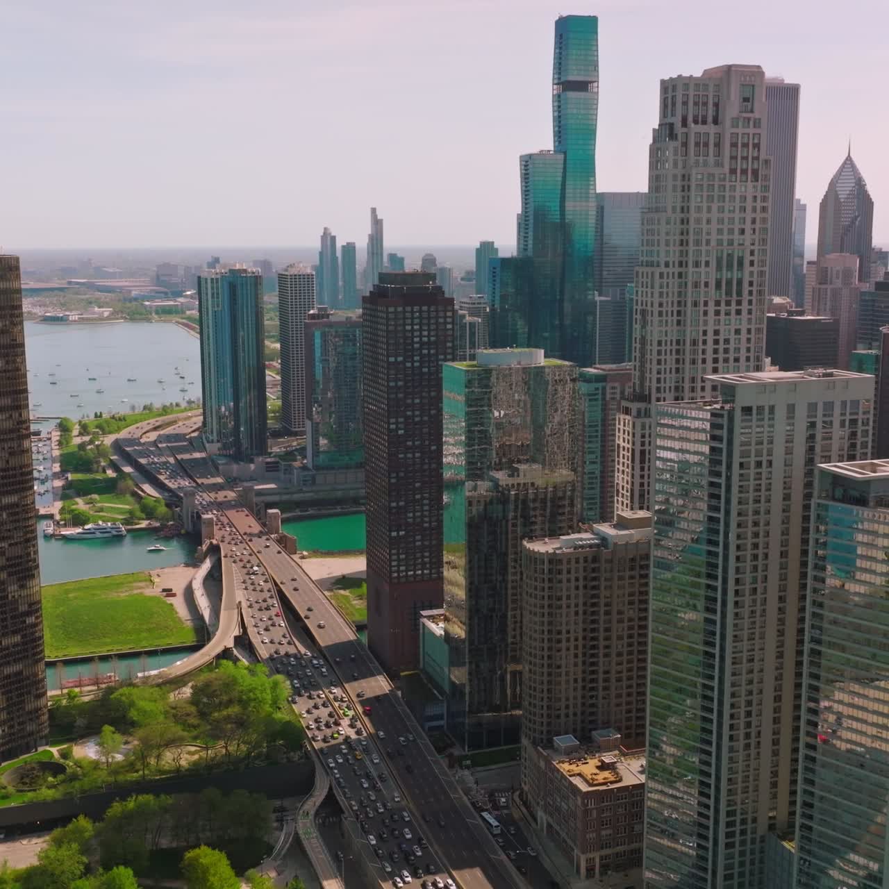 Incredible skyscrapers neighboring turquoise waters of the Lake Michigan. Drone footage of Chicago buildings, green areas, multi-lane roads and scenic view of a lake