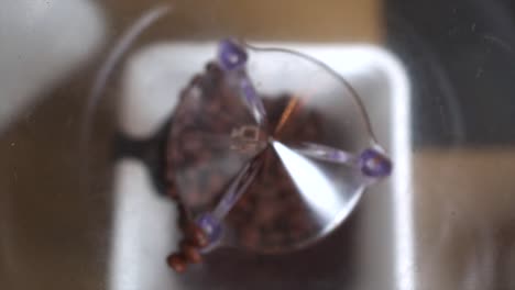los granos de café marrones caen en el molinillo, cerca de hacer café recién molido