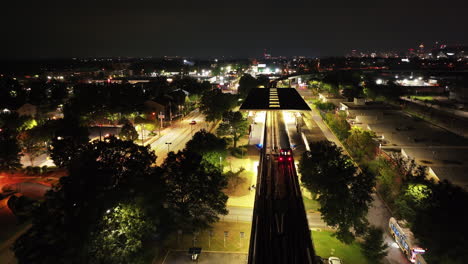 vista posterior del tren de metro que llega a la estación elevada en el vecindario urbano