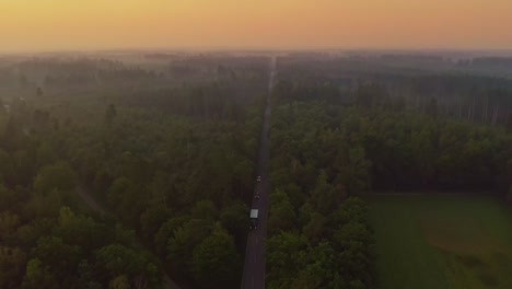 Cars a driving down a street in early sunrise colors swing down shot by a drone camera