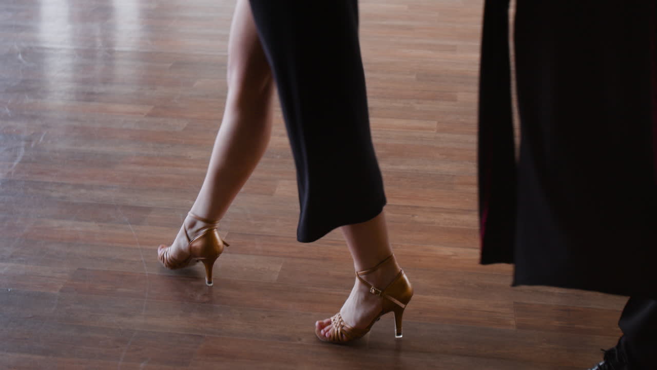 Two individuals in black attire walking through a dance studio
