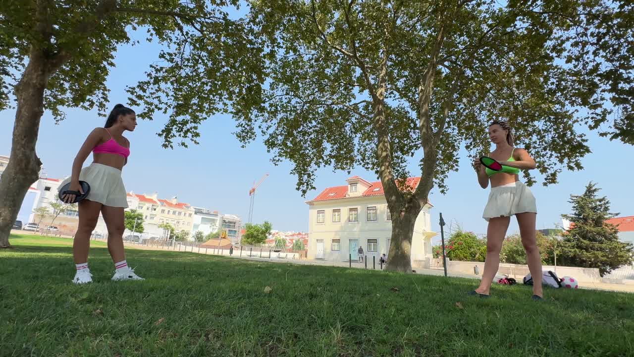 Two women playing paddle in a park