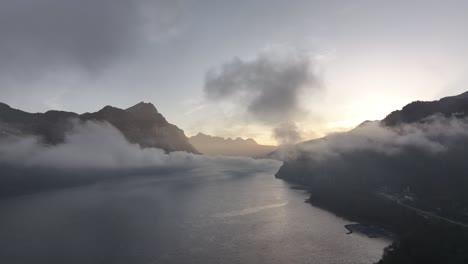 misty walensee at sunrise with mountain silhouettes and dramatic cloud cover