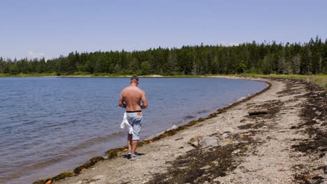 adult, white, shirtless male walking down a new england beach in late summer