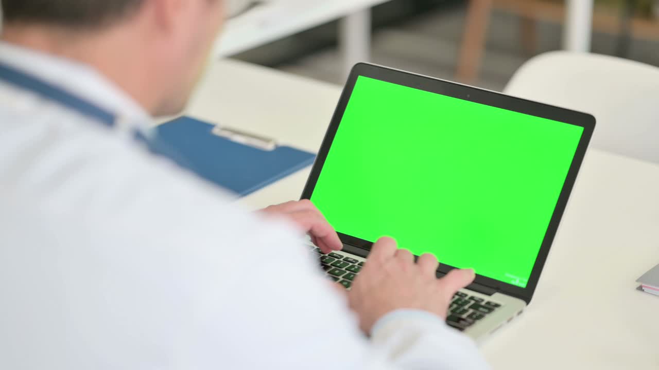 médico masculino trabajando en una computadora portátil con pantalla cromada