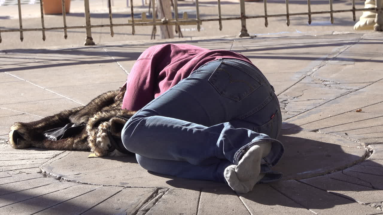 Close up of a homeless woman without shoes sleeping on the street
