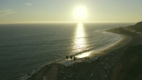 cinematic aerial view of traffic on california state route one at sunset with pacific coastline and surrounding nature