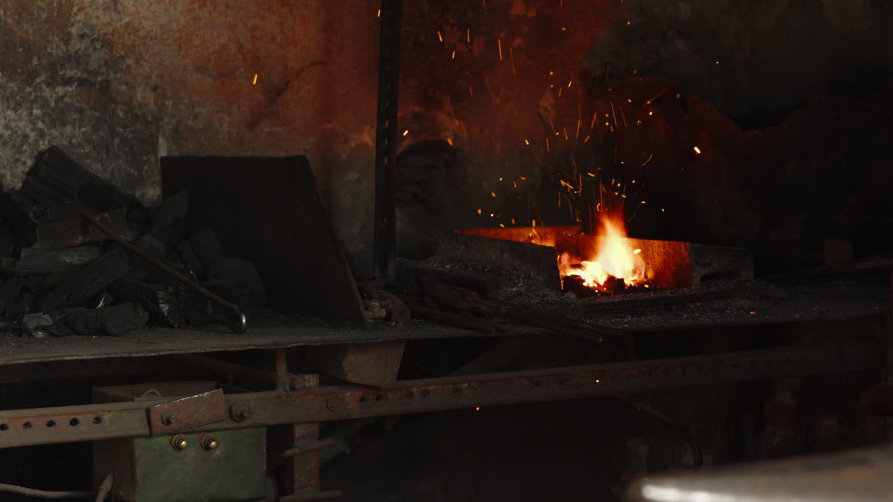 A blacksmith's workshop, with the coal forge running, incandescent particles flying through the air