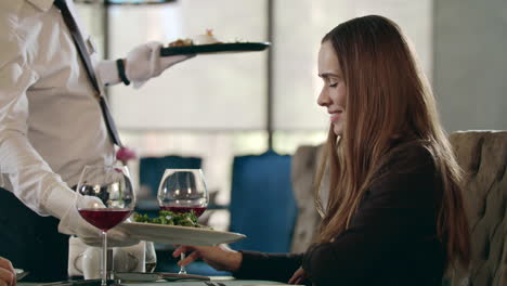 businesswoman getting ordered food in restaurant. waiter serving meal