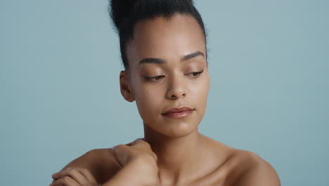 portrait attractive young african american woman with smooth healthy skin looking confident gorgeous female enjoying flirtatious sensual beauty on blue background skincare concept